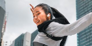 一位佩戴 Bose QuietComfort 消噪耳塞在户外跳舞的女孩