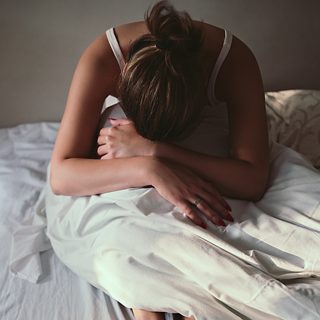 醒来后倍感疲乏的女人坐在床边