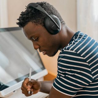 一位男士在工作时佩戴 Bose Noise Cancelling 700 无线消噪耳机