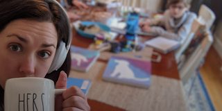 一位女士戴着 Bose 700 无线消噪耳机在家办公，身边是她的家人，