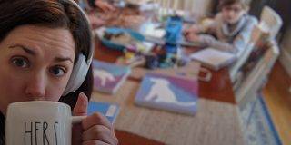 一位女士戴着 Bose 700 无线消噪耳机在家办公，身边是她的家人，