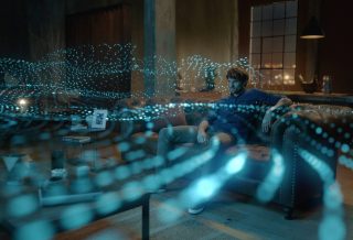 一位男士正在看电视,描绘 Bose 家庭娱乐扬声器 850 放射出的 Dolby Atmos 声波