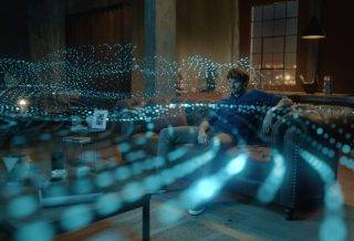 一位男士正在看电视，描绘 Bose 家庭娱乐扬声器 850 放射出的 Dolby Atmos 声波