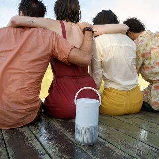 一群好友在码头，聆听 Bose 便携式智能扬声器播放的音乐