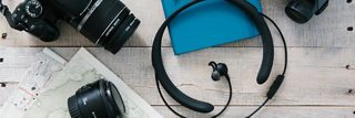 桌上有一副 Bose QuietControl 30 无线耳机、一台相机、一个笔记本