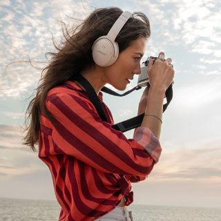 佩戴 Bose QuietComfort 45 消噪耳机在海滩上拍照的女士