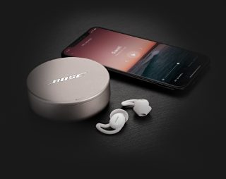 显示 Sleep App 的智能手机和装在充电盒中的 Bose 遮噪睡眠耳塞 II