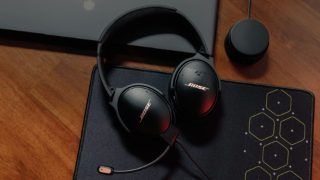 摆在桌子上的 Bose QuietComfort 35 II 游戏耳机和桌面音量控制器