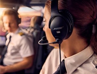 一名商业飞行员的侧脸和 Bose A30 航空耳机的侧视图，她转身与副驾驶交谈