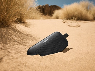 沙地上放着的 Bose SoundLink Flex 便携式扬声器(第 2 代)。