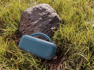 草地上靠着岩石放着的 Bose SoundLink Max 手提音箱