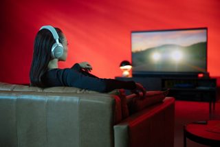 一位佩戴 Bose QuietComfort 消噪耳机 Ultra 的女士正在使用 SimpleSync 通过 Bose 家庭娱乐扬声器 Ultra 观看电视节目